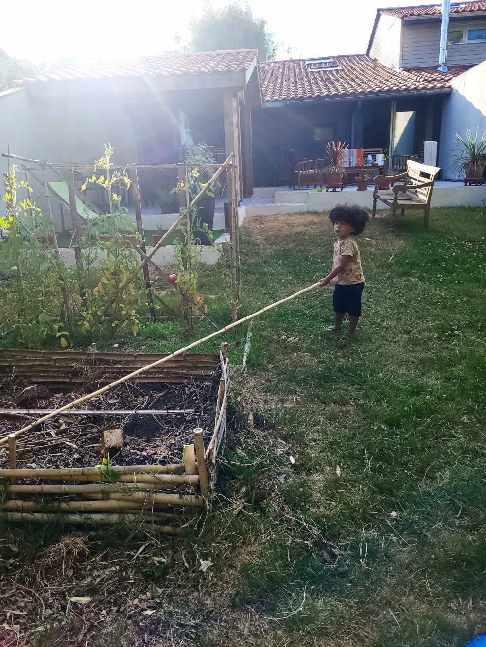 Adao joue avec un baton dans le jardin d'Adrien et Claire